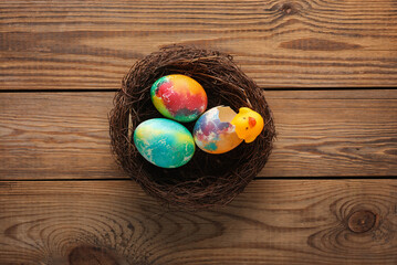 Multicolored Easter eggs in nest on wooden table. Top view