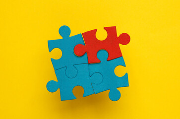 Blue and red jigsaw puzzle pieces on a yellow background. Business concept