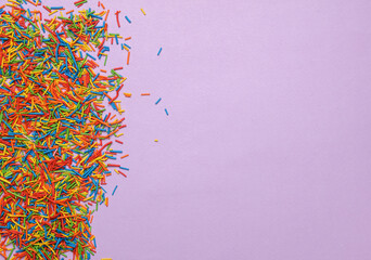 Sprinkles for cake on purple pastel background. Copy space