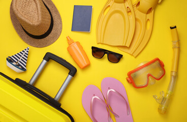 Yellow suitcase, luggage with travel accessories on yellow background. Summer vacation, travel, relocation concept. Top view. Flat lay