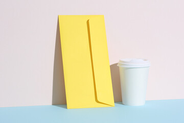Creative layout with white coffee cup and envelope on pastel bright background. Minimalism