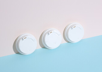 White lids for hot drinks on a pastel background with shadow. Creative layout, minimalism