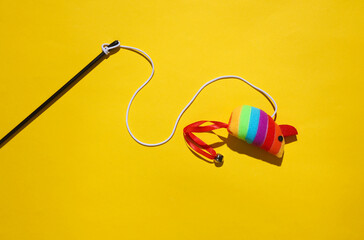Naklejka premium Toy mouse on a rope, yellow background. Cat toys for active game