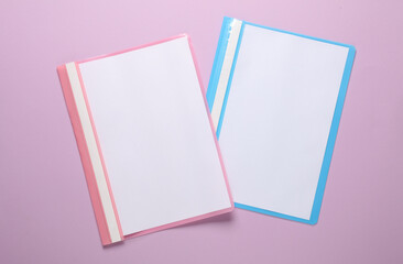 Two plastic folders with paper sheets on a purple background