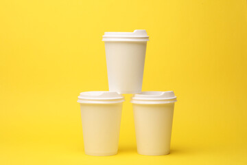 Take-out white cardboard coffee cups with lid on yellow background