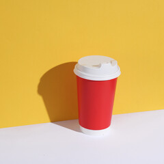 Red disposable cup on yellow-white background with shadow