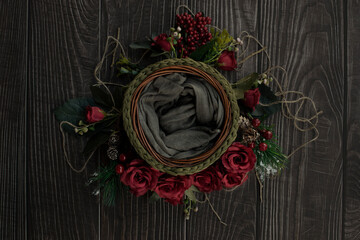 Newborn digital backdrop with crochet basket, red handmade roses and christmas decoration on wooden background. Flat lay. Top view.Newborn christmas background. smooth oil paint efect in flowers.