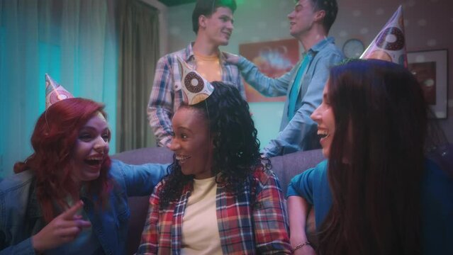 African American girl takes a selfie with friends. A group of young people take pictures, show the victory gesture, send air kisses and stick out their tongue. Friends have fun at a house party.