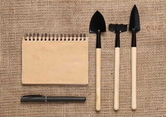 Set of gardening tools with a notepad on burlap