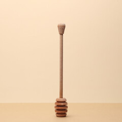 Wooden spoon for honey on a two tone beige background