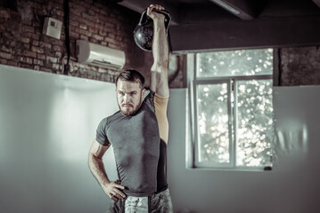 Young athletic man exercising with a kettlebell in a gym