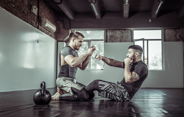 Two male fighters train muscles in a sports hall