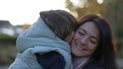 Fototapeta premium Happy mother and child relationship. Small son kissing mom in cheek. Real life moterhood lifestyle. loving caring parenting motherhood lifestyle