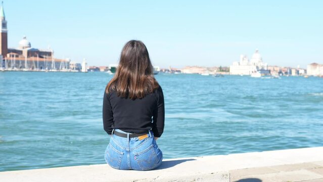 Female tourist looks at the fascinating view of the sea and the city life of the city on the water.