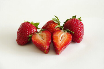 Strawberries on a white background. Ripe strawberries. Three berries and two heart halves.