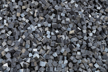 Basalt cubes as background. Pile of natural stone cubes for making outdoor pavement tiles.