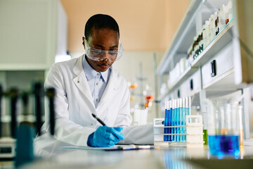 Black female scientist analyzing research data while working in laboratory.