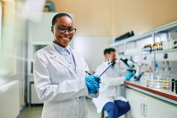 Portrait of happy black female scientist in lab looking at camera. - obrazy, fototapety, plakaty