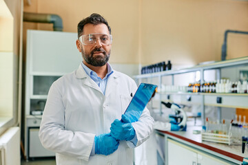 Male biochemist working in laboratory and looking at camera.