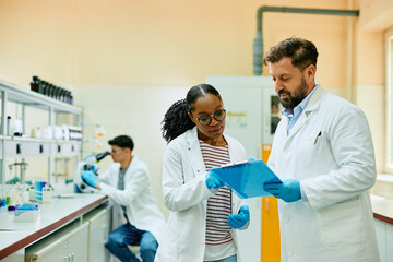 Two scientist analyzing research data while working in laboratory.