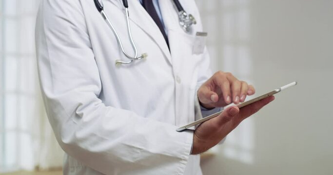 Tablet, healthcare and hands of doctor doing research in a hospital before a consultation. Technology, professional and closeup of male medical worker doing data analysis on mobile in medicare clinic