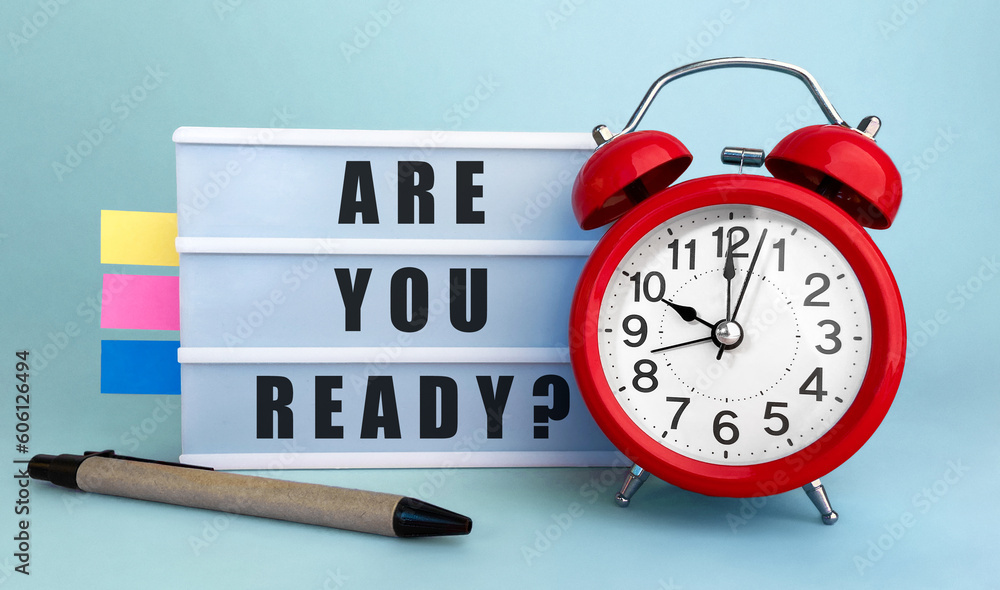 Poster text are you ready written on the lightbox with alarm clock and colorfull stickers on blue backgroun