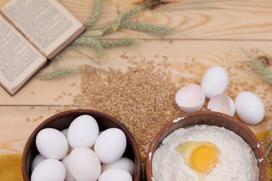 Broken shell egg, chicken eggs, wheat flour, wheat grain scattered on the table, wooden background, recipe book background image, for presentations