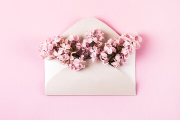 Pink lilac flowers in an envelope on a pink background. Greeting card. Flat lay, copy space