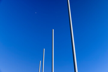 Fototapeta premium a group of empty metal flagpoles against a blue sky background