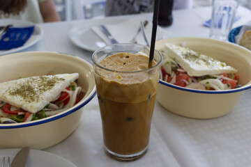Ice coffee in a tavern on the Chaltidiki peninsula. Two bowls of Greek salad as a refreshing meal during the heat, Greece