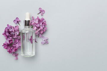 Obraz na płótnie Canvas Face serum with flowers on color background, top view