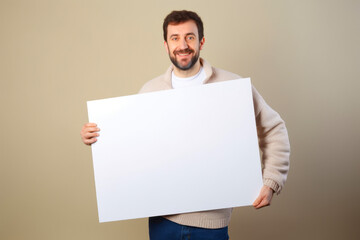 Portrait of a smiling man holding a white sheet of paper on grey background