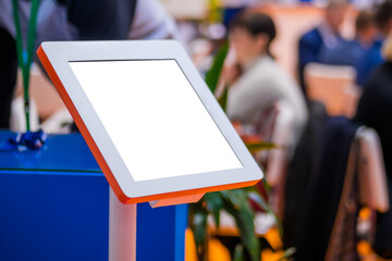 Electronic multimedia tablet kiosk with blank white display at exhibition, trade show, conference -...