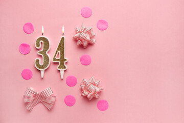 Number 34 on pastel pink background with festive decor. Happy birthday candles. The concept of celebrating a birthday, anniversary, important date, holiday. Copy space. Banner