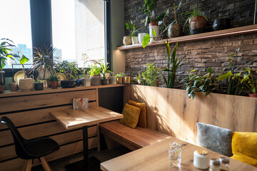 Interior of modern vegan restaurant with many plants as decoration with wooden tables and stone...