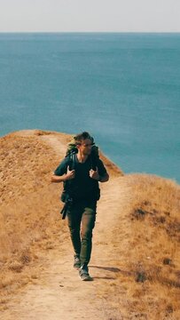 The traveler with backpack hiking above the sea