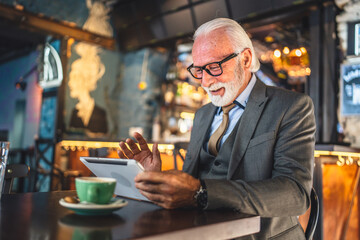 Senior man businessman business owner use digital tablet sit at cafe