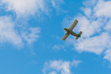 Green biplane, retro airplane flying in blue sky and doing stunts at Air Show. Performance,...