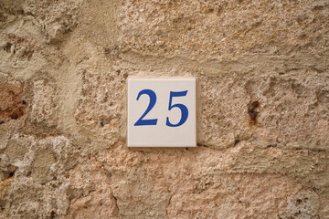 25 ceramic number plate on old stone wall