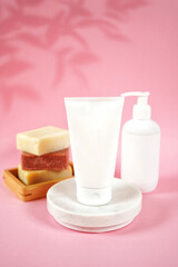 Cosmetic skincare blank container mockups in a styled setting. Pink background with leaves shadow photography. 