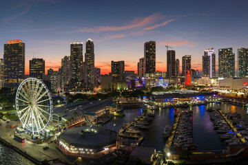 American urban landscape at night. Miami marina and Skyviews Observation Wheel at Bayside Marketplace with reflections in Biscayne Bay water and skyscrapers of Brickell, city's financial center - obrazy, fototapety, plakaty