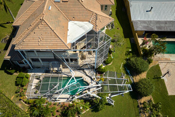Hurricane Ian destroyed swimming pool lanai enclosure on house yard in Florida residential area. Natural disaster and its consequences