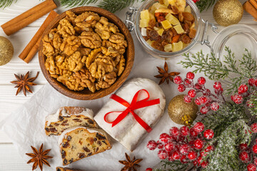 Fototapeta premium Christmas stollen on a texture table. Traditional German Christmas dessert cut into pieces. Cake with nuts, cinnamon, raisins, dried fruits and marzipan. baking for christmas. Place for text. 