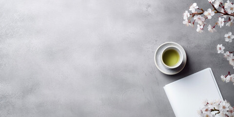 Versatile japan inspired background with copy space. Cup of green tea, sakura and blank paper on light grey concrete