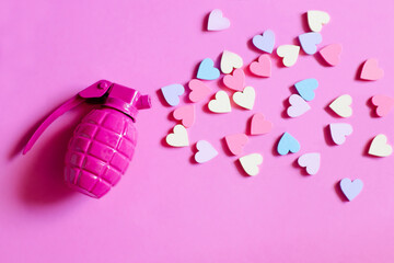 Pink toy hand grenade bomb with multicoloured small hearts on a pink background. The concept of peace and life without war. Make Love Not War