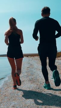 The man and woman are jogging on the sea shore. slow motion