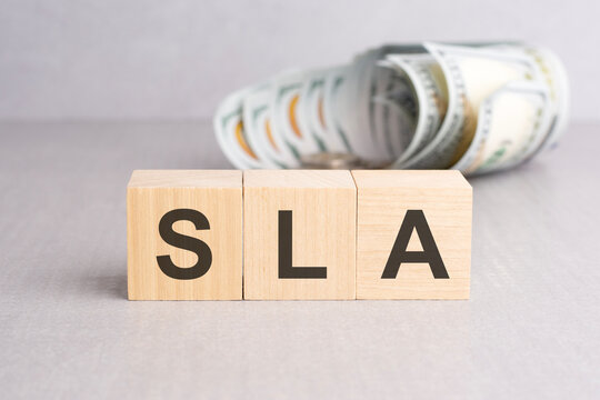 SLA - short for Service Level Agreement. wooden cubes with text, grey background