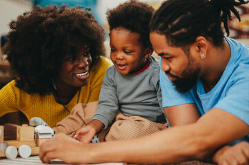 A happy african american family is having fun together with a Montessori toy at home.