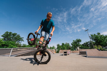 A middle-aged man with tattoos is practicing an extreme sport with a bmx in a skate park.