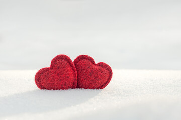 Fototapeta premium cute red hearts together on white fluffy snow, love concept, valentines day background